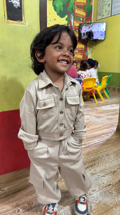 A smiling toddler standing in the classroom