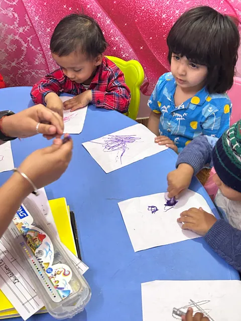 Toddlers colouring with crayons at a table