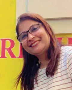 Poonam Sharma, founder of alphabet CRÈCHE, smiling in front of the alphabet CRÈCHE birthday wall