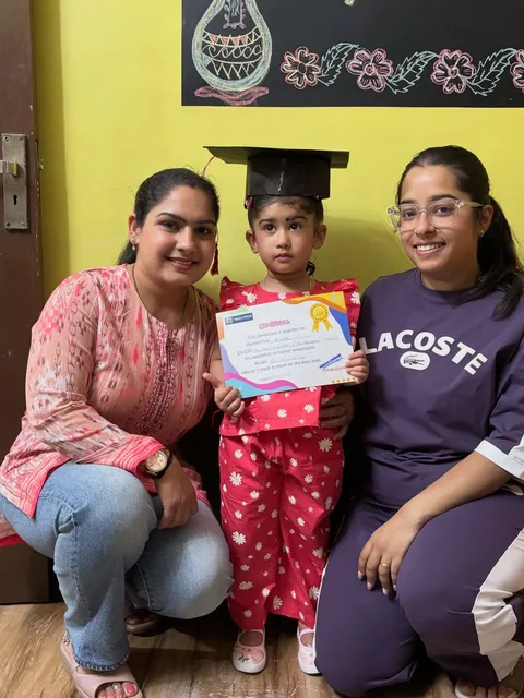 Two teachers with a girl in a graduation cap holding her certificate