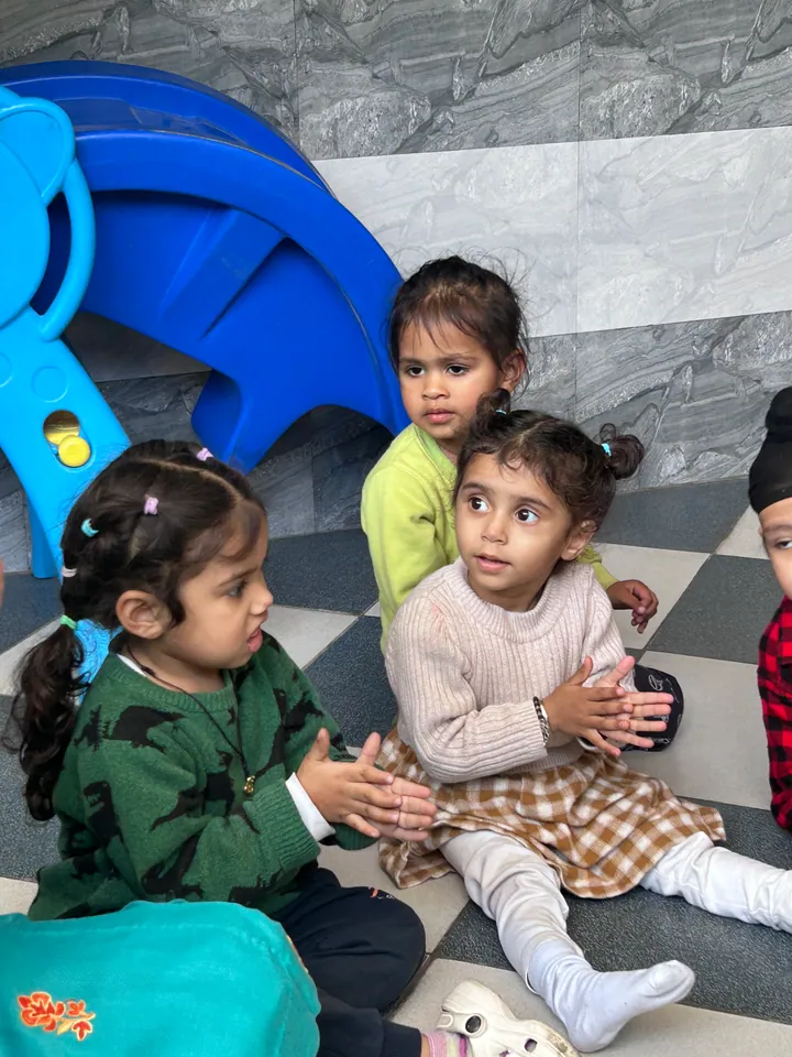 Two little girls clapping on the floor of the playing area