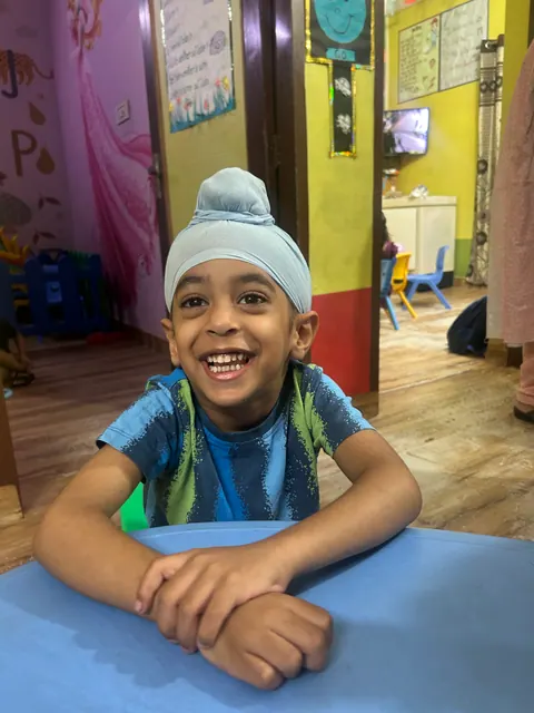 An older boy laughing at a classroom table