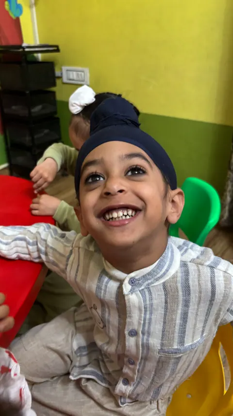A boy in a navy patka laughing and looking up
