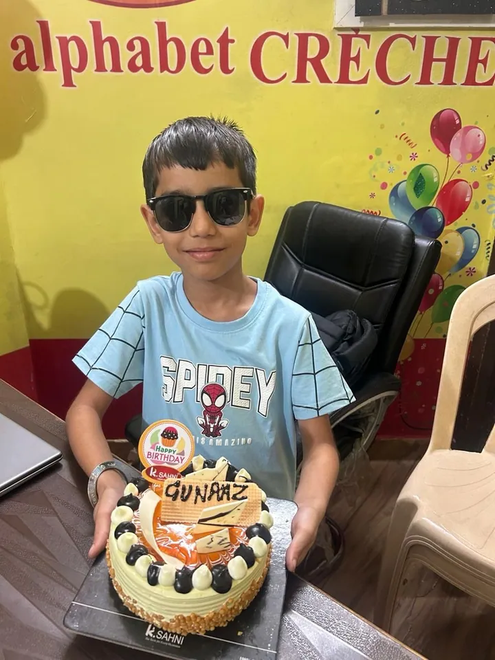 The birthday boy in sunglasses holds up his cake in the office