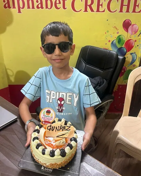 The birthday boy in sunglasses holds up his cake in the office
