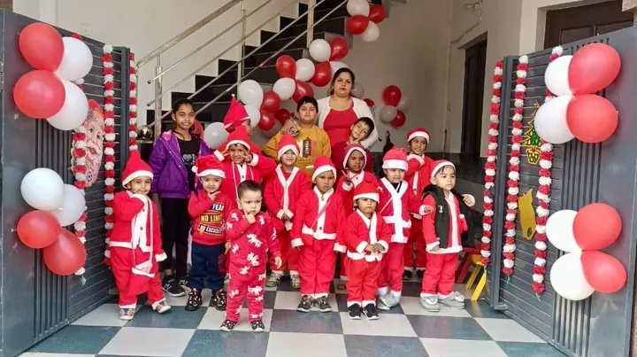 The children in red Santa suits and hats stand together at the entrance, red and white balloons on both sides and the stairs behind