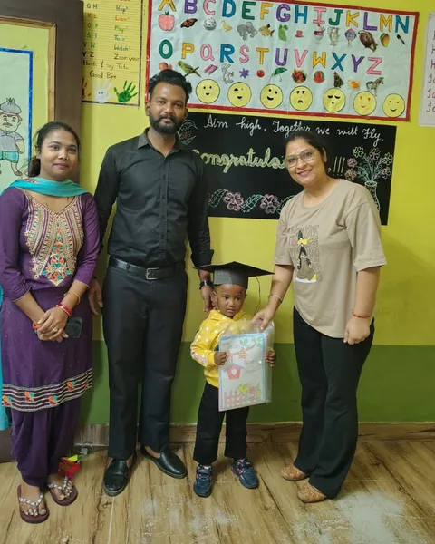 Poonam ma’am hands a certificate to a small graduate in a cap, with the family beside them