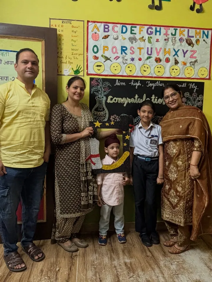 A family stands with their children in front of the “Aim high, together we will fly” congratulations board