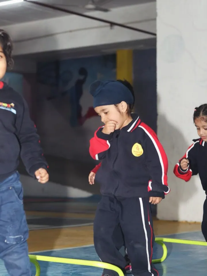 A child in a winter uniform stepping through rings laid out on a hall floor