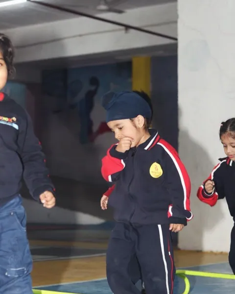 A child in a winter uniform stepping through rings laid out on a hall floor
