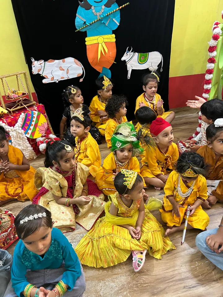 A group of children dressed in yellow for Janmashtami, some with peacock feathers