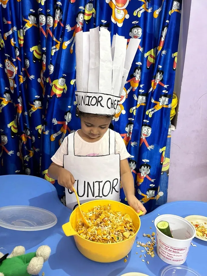 A small girl in a Junior Chef apron stirs the big yellow bowl