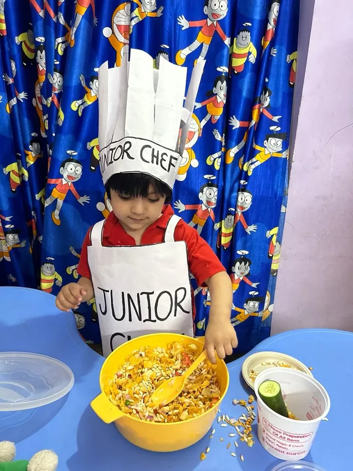 A little boy in a Junior Chef hat and apron mixes with a big spoon