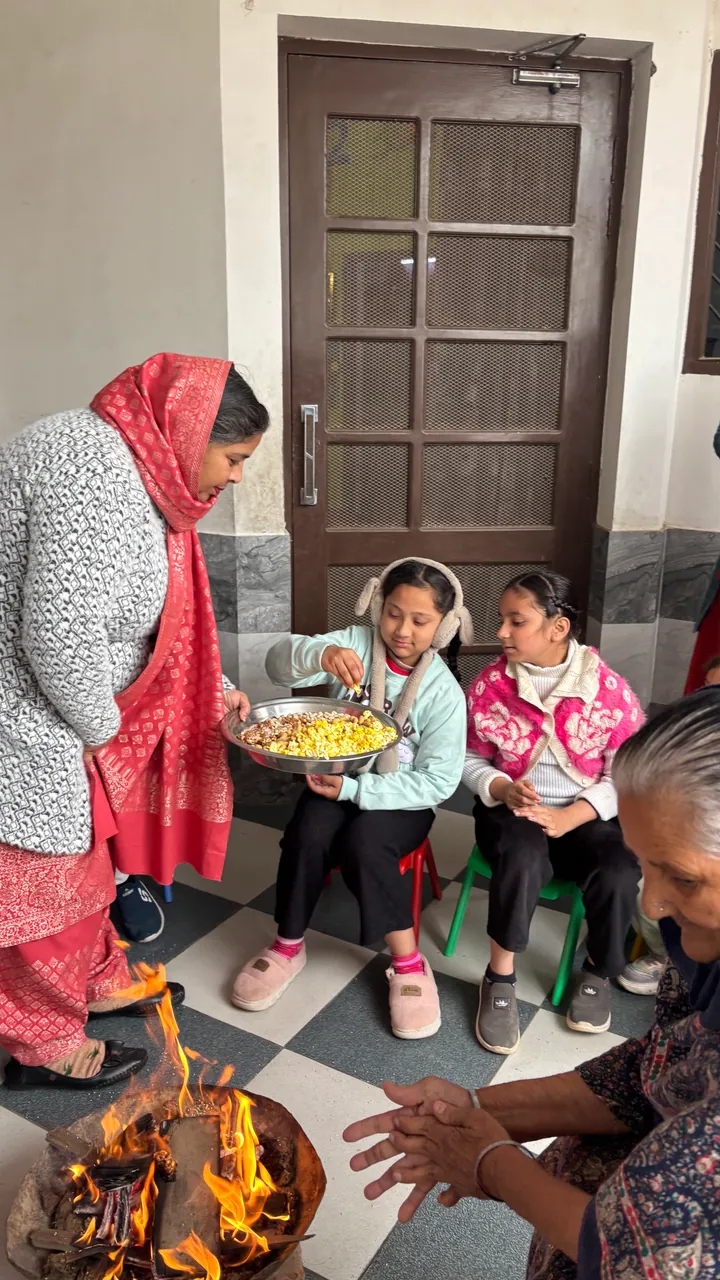 Children reach into the plate of popcorn Manjeet ma'am holds out