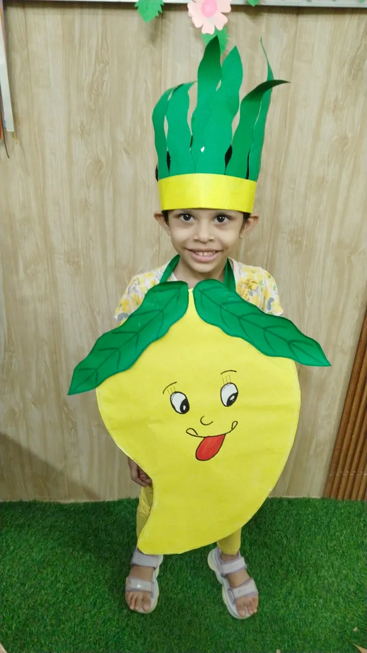 A smiling child in a mango costume