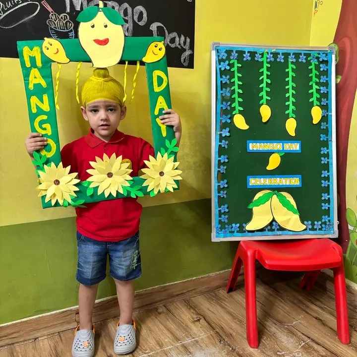A boy in a yellow patka and red shirt holds the Mango Day frame